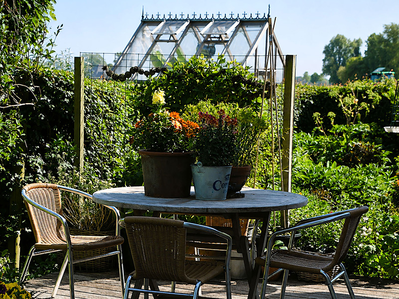 Rond tuinterras met tafel en stoelen voor de glazen kas